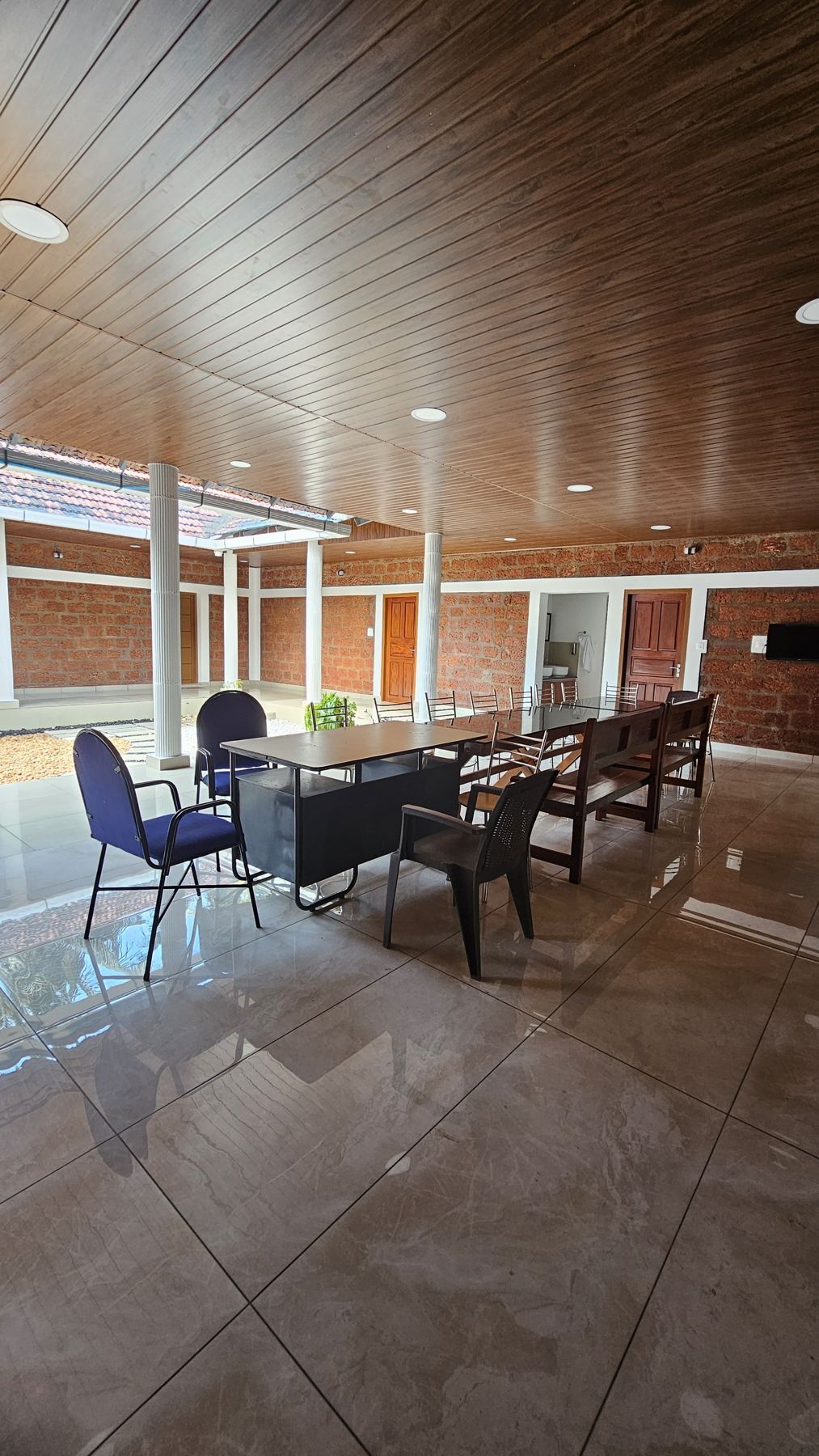 Spacious hall with wooden ceiling, tiled floor and dining chairs